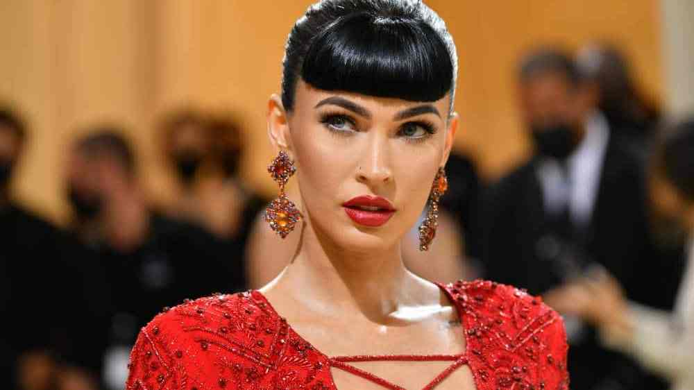 Megan Fox wears a red dress with red earrings and matching lipstick