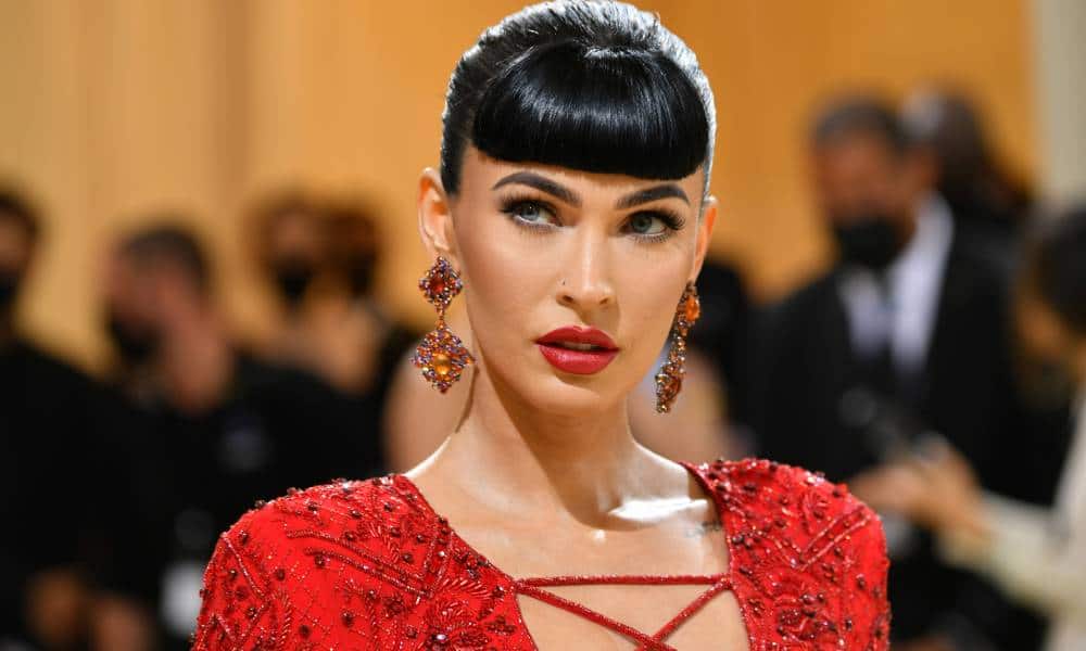 Megan Fox wears a red dress with red earrings and matching lipstick