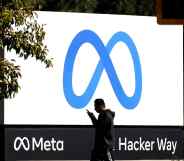 A person walks past a billboard showing the Meta logo