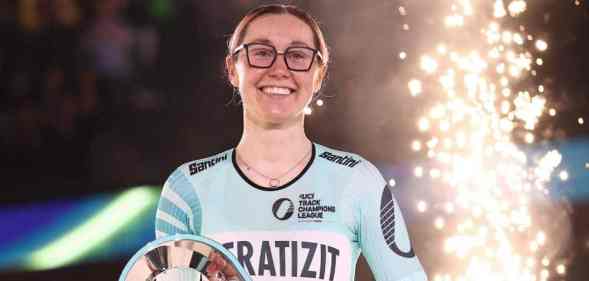 Katie Archibald holds a trophy as a sparkler goes off behind her