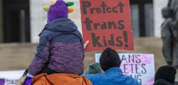 Protester holds a sign that reads 'protect trans kids'