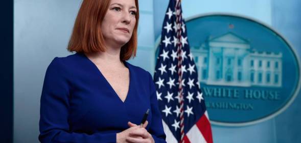 Jen Psaki stands in front of a US flag while attending a press conference at the White House