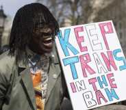 A demonstrator holds a placard demanding a ban on trans conversion therapy at a protest opposite Downing Street