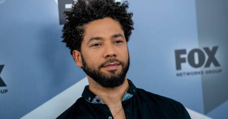 Jussie Smollett stares off camera while wearing a dark shirt with blue elements on the collar