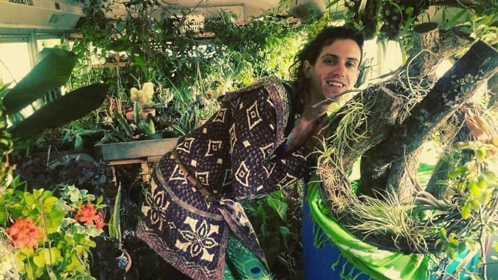 Fern Feather, a white trans woman, is seen surrounded by plants