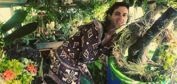 Fern Feather, a white trans woman, is seen surrounded by plants