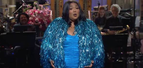 Lizzo wears a bright blue dress and a sparkly blue jacket during her opening monologue on Saturday Night Live