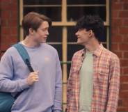 Actors Kit Connor and Joe Locke play characters Nick Nelson and Charlie Spring in the Netflix series Heartstoppers. In the scene, they are standing at a train station.