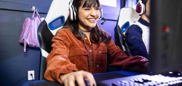 A gamer wearing a headseat, clicking a mouse, smiling