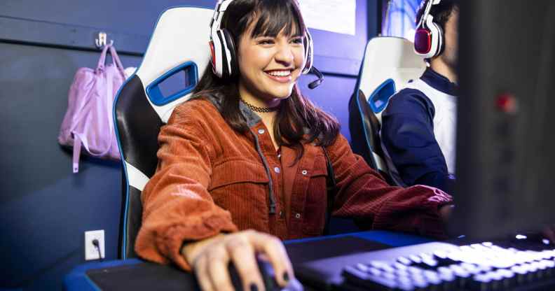 A gamer wearing a headseat, clicking a mouse, smiling