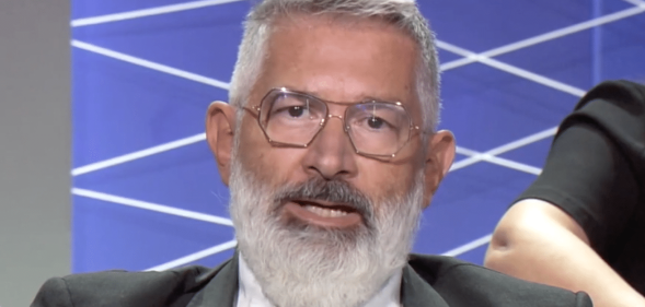 Paolo Rondelli, a white man with grey hair and a grey beard, wearing square metal glasses