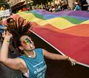 A participant dances while holding a large rainbow flag during the Athens Gay Pride