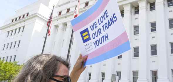 A protester props up a sign that says: 'We love our trans youth'