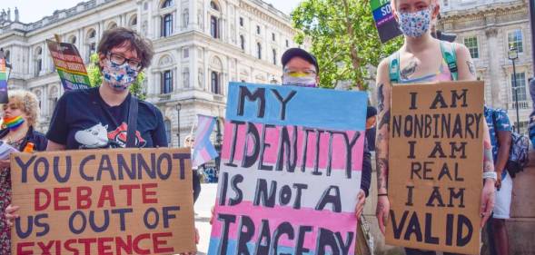 several people hold up signs during a trans rights protest one reads "you cannot debate us out of existence", "my identity is not a tragedy" and "I am non-binary, I am real, I am valid"