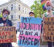 several people hold up signs during a trans rights protest one reads "you cannot debate us out of existence", "my identity is not a tragedy" and "I am non-binary, I am real, I am valid"