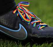A close-up of a football boot showing laces in rainbow pride colours
