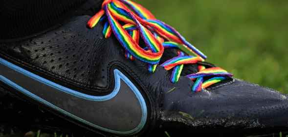 A close-up of a football boot showing laces in rainbow pride colours