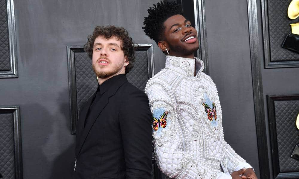 Jack Harlow wears an all black outfit as he stands back to back with Lil Nas X who is wearing a decorative white outfit