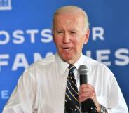 President Joe Biden speaks into a microphone while wearing a white button up shirt and a dark tie with stripes
