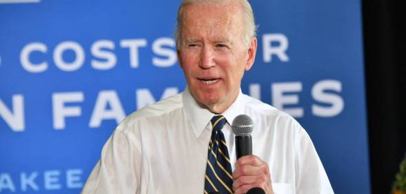 President Joe Biden speaks into a microphone while wearing a white button up shirt and a dark tie with stripes