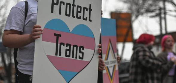 An activist holds a placard with the words 'Protect Trans Youth'