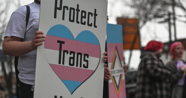 An activist holds a placard with the words 'Protect Trans Youth'