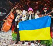 Eurovision winners Kalush Orchestra pose onstage with their trophy and Ukraine's flags