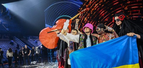 Ukraine's Kalush Orchestra hold the Eurovision trophy and a Ukraine flag
