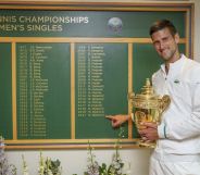 Novak Djokovic stands next to the Wimbledon men's honours board, which does not use titles