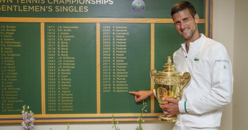 Novak Djokovic stands next to the Wimbledon men's honours board, which does not use titles