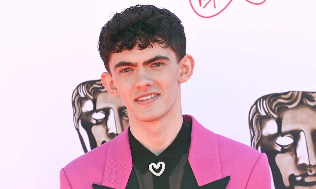 Actor Joe Locke wearing a pink suit jacket over a black shirt poses for a photo at the 2022 Virgin Media British Academy Television Awards