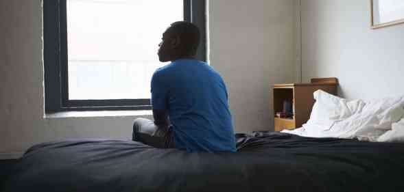 A stock photograph of a man sitting on a bed