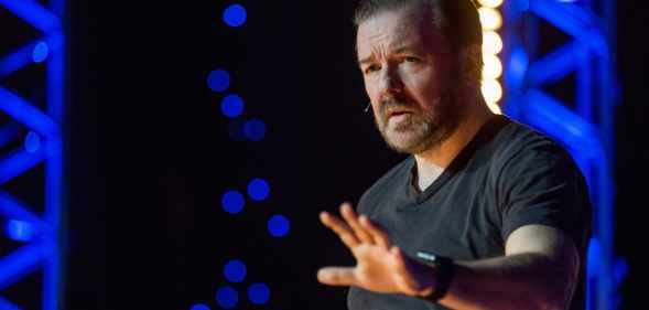 Ricky Gervais gestures while performing on stage