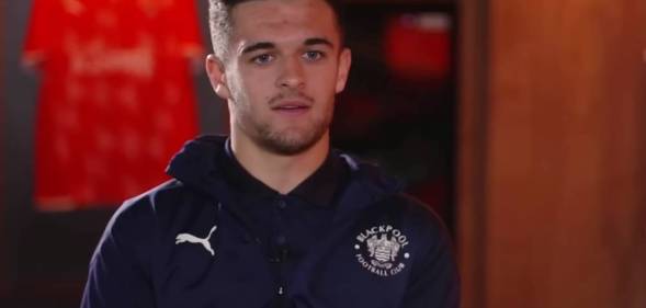 Blackpool footballer Jake Daniels stars at the camera while wearing a dark top