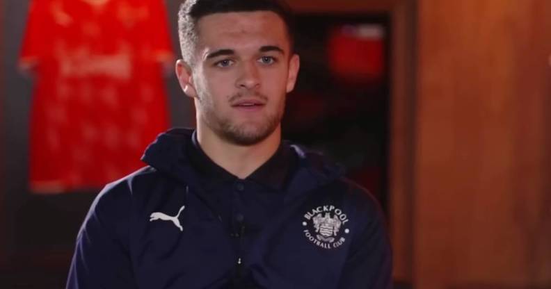 Blackpool footballer Jake Daniels stars at the camera while wearing a dark top