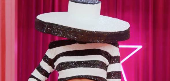 A drag queen appears on Drag Race All Stars 7 wearing a black and white outfit with a giant hat