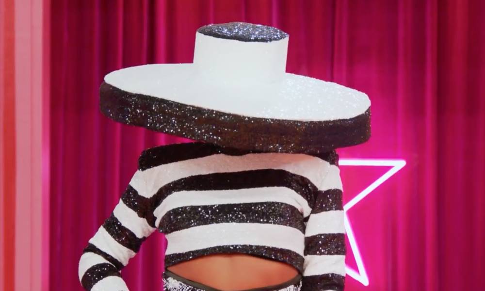 A drag queen appears on Drag Race All Stars 7 wearing a black and white outfit with a giant hat