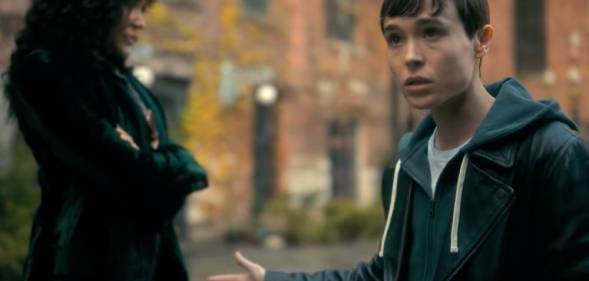 A screenshot from the trailer for Umbrella Academy season three in which Elliot Page's character Viktor talks to someone off screen and holds up their arm
