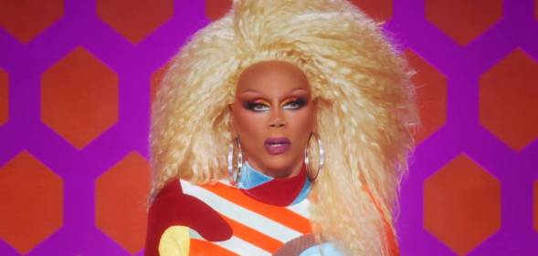 Iconic Drag Race host RuPaul wears a bright blonde wig, red white blue and yellow jumpsuit as she judges All Stars 7