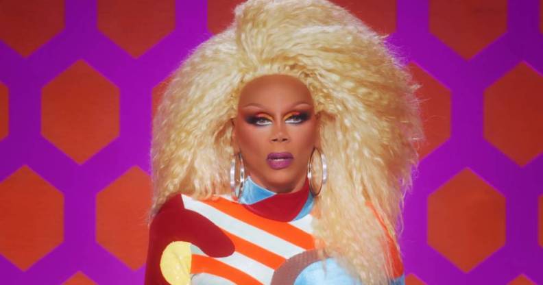 Iconic Drag Race host RuPaul wears a bright blonde wig, red white blue and yellow jumpsuit as she judges All Stars 7