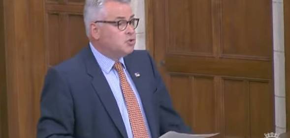Tory MP Tim Loughton wears a blue shirt, orange tie and dark blue suit jacket during a parliament debate on non-binary legal recognition