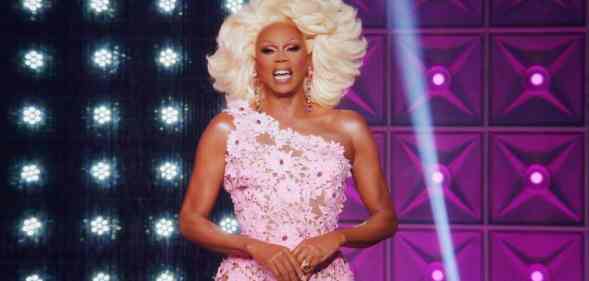 Drag Race icon RuPaul smiled at the camera while wearing a blonde wig and pink floral dress on the set of All Stars 7