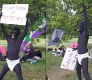 A man wearing an all-black morph suit with a sign reading, 'right side of history' and: 'real feminist'
