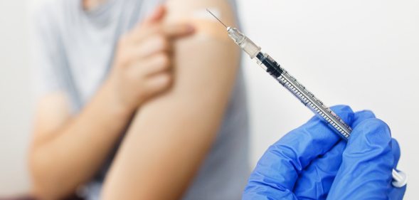 A doctor holds a syringe.