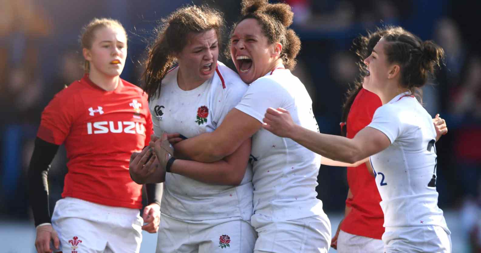 English women's rugby players cheer and shout on the field