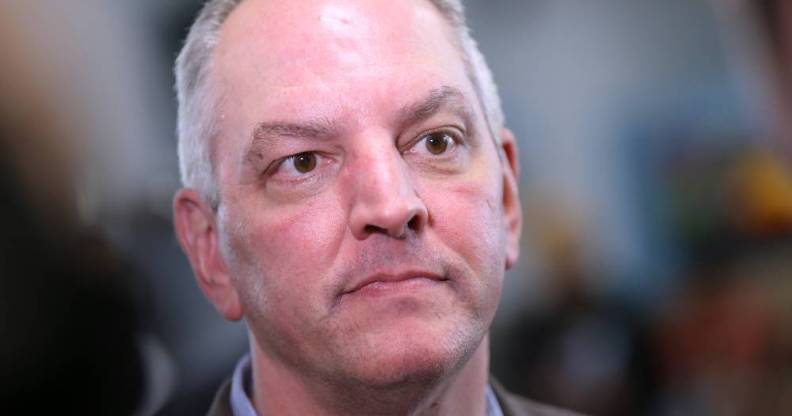 Louisiana governor John Bel Edwards stares slightly off camera while wearing a blue shirt and grey jacket