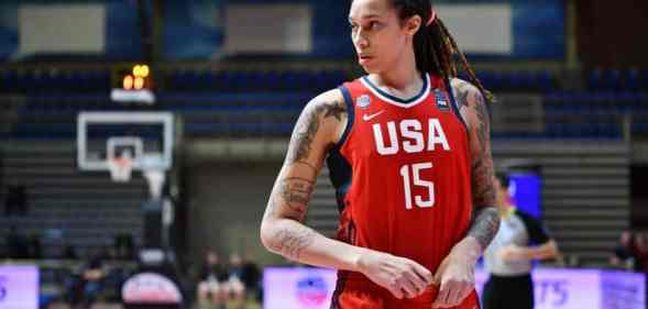 Brittney Griner wears a red basketball jersey with 'USA' and '15' written in white with blue panelling on the sides as she runs down a basketball court. Griner has her hair styled in locks and has multiple tattoos on both arms