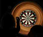 Silhouette of lady throwing darts at a dartboard