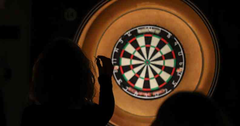 Silhouette of lady throwing darts at a dartboard