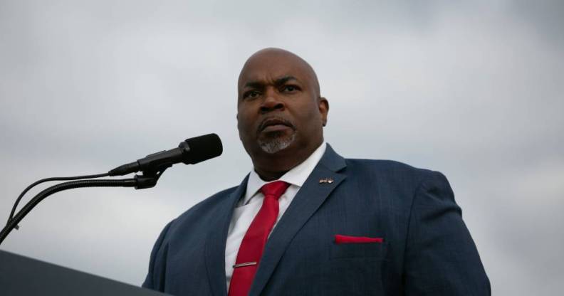 North Carolina lieutenant governor Mark Robinson stands at a podium while wearing a white button up shirt, red tie and blue suit jacket with a red pocket square